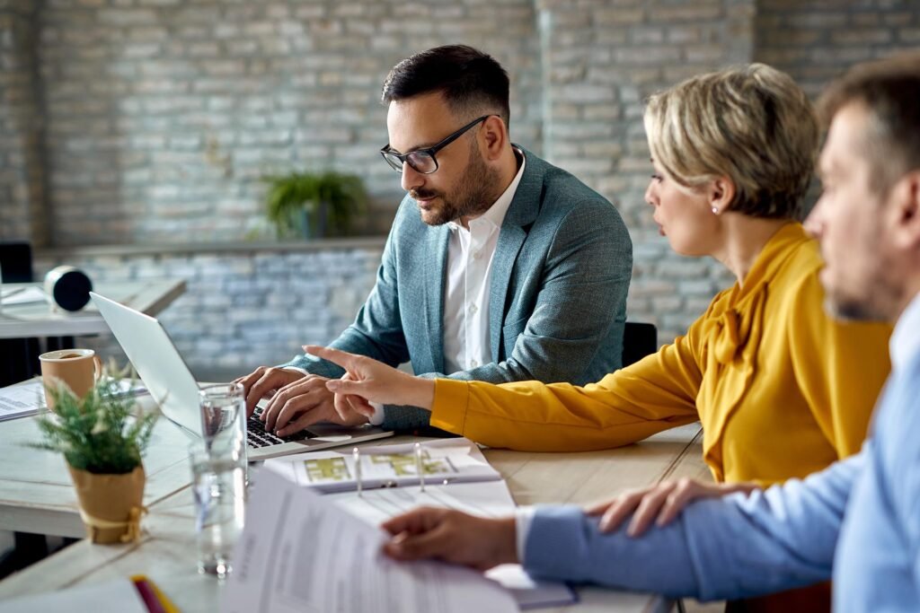 Real estate agent using laptop while having a meeting with a couple in the office.