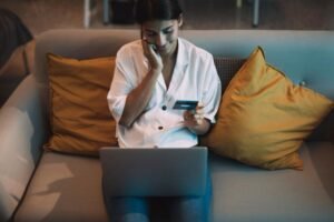 a girl sitting on a couch and using her laptop